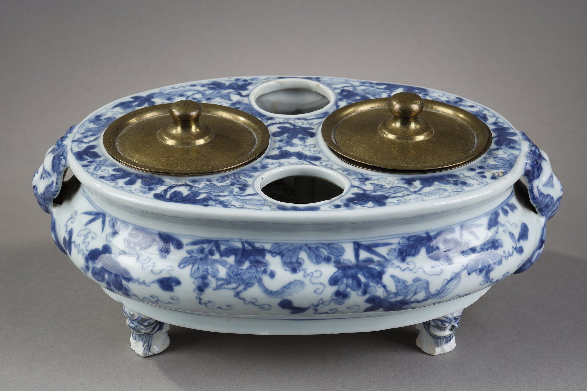 Oil carrier-vinaigrier porcelain blue-white oval shape resting on three feet adapted posteriorly in inkwell with decoration of loirs in the grapes the handles in the shape of head of lions and rings and feet in the shape of masks of Taotie  - China Kangxi period 1662/1722